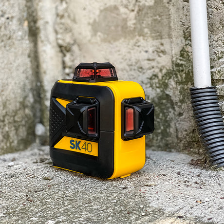Tracciatore laser su appoggiato su pavimento e muro grezzi