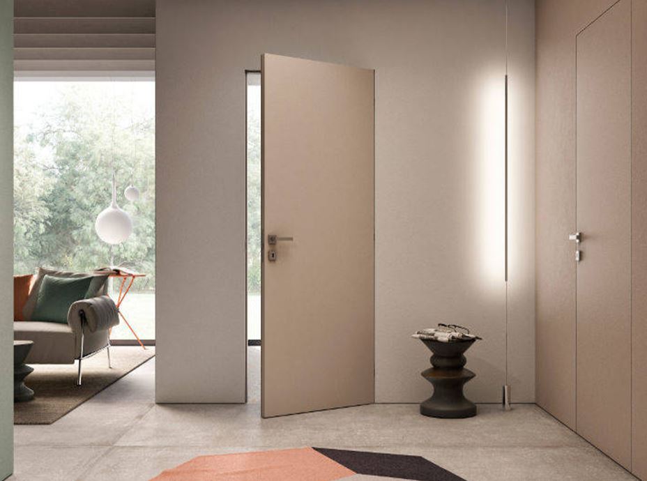 Porta battente raso muro senza cornici, color sabbia caldo in continuità con il muro